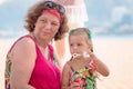 Grandmother enjoying day with granddaughter while blowing soap bubbles on the beach near the sea Royalty Free Stock Photo
