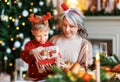 Grandmother with excited girl grandson unpacking Christmas gift box near decorated xmas tree Royalty Free Stock Photo