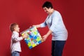 Grandmother gives a gift to grandson on a red background Royalty Free Stock Photo