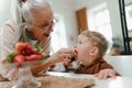 Grandmother giving homegrown strawberries to her little grandson.