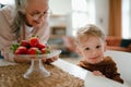 Grandmother giving homegrown strawberries to her little grandson.