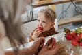 Grandmother giving homegrown strawberries to her little grandson.