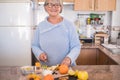 Grandmother with glasses cut fruit and smiling - lifestyle health, healhy - kitchen in the background - cooking at home