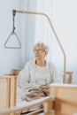 Grandmother with glasses is sitting on the bed