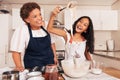 Grandmother and graddaughter having fun while preparing dough on kitchen. Happy girl with spoon