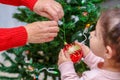 Grandmother and grandchild decorate the Christmas tree with baubles indoors. Portrait loving family close up.