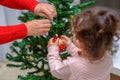 Grandmother and grandchild decorate the Christmas tree with baubles indoors. Portrait loving family close up.