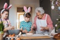 Grandmother with grandchildren preparing traditional easter meals, kneading dough for easter cross buns. Passing down Royalty Free Stock Photo