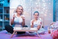 Grandmother and granddaughter are eating cookies with milk at night at home. Royalty Free Stock Photo