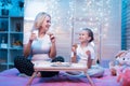 Grandmother and granddaughter are eating cookies with milk at night at home. Royalty Free Stock Photo