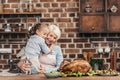 grandmother and granddaughter embracing on kitchen and looking at freshly prepared turkey