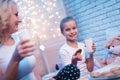 Grandmother and granddaughter are enjoying milk and cookies at night at home. Royalty Free Stock Photo