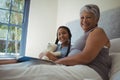 Grandmother and granddaughter holding photo album in bed room Royalty Free Stock Photo