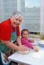 Grandmother and granddaughter knead the dough