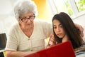 Grandmother and granddaughter looking at laptop computer together at home Royalty Free Stock Photo