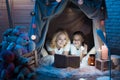 Grandmother and granddaughter are reading book in blanket house at night at home. Royalty Free Stock Photo