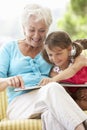 Grandmother And Granddaughter Reading Book On Garden Seat Royalty Free Stock Photo