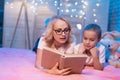 Grandmother and granddaughter are reading book before sleep at night at home. Royalty Free Stock Photo