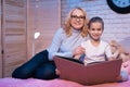 Grandmother and granddaughter are reading book at night at home. Royalty Free Stock Photo