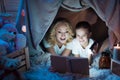 Grandmother and granddaughter are reading fairy tales in blanket house at night at home. Royalty Free Stock Photo