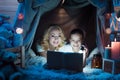 Grandmother and granddaughter are reading fairy tales in blanket house at night at home. Royalty Free Stock Photo