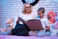 Grandmother and granddaughter are reading fairy tales book at night at home. Royalty Free Stock Photo