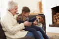 Grandmother And Granddaughter Relaxing At Home With Pet Dog