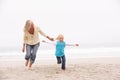 Grandmother And Granddaughter Running Along Beach Royalty Free Stock Photo