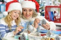 Grandmother and granddaughter in Santa hats making New Year& x27;s decorations