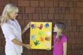 Grandmother and granddaughter showing colorful multiple hand prints against brick wall