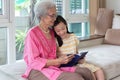 Grandmother and granddaughter sitting on sofa and reading book h Royalty Free Stock Photo