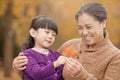 Grandmother and granddaughter smiling and looking at leaf together