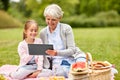 Grandmother and granddaughter with tablet at park Royalty Free Stock Photo