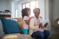 Grandmother and granddaughter using digital tablet on sofa in living room Royalty Free Stock Photo