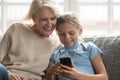 Grandmother and granddaughter using smartphone at home together Royalty Free Stock Photo