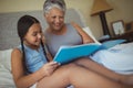 Grandmother and granddaughter watching photo album together in bed room Royalty Free Stock Photo