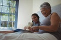 Grandmother and granddaughter watching photo album together in bed room Royalty Free Stock Photo