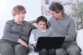Grandmother , grandfather and grandson looking at laptop screen while relaxing on the couch Royalty Free Stock Photo