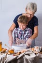 Grandmother with grandson cooking, kneading dough, baking in the kitchen