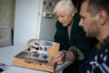 Elderly widowed woman holds photos of her deceased husband and gets emotional on valentine`s day remembering old times. Royalty Free Stock Photo