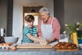 Grandmother with grandson preparing traditional easter meals, kneading dough for easter cross buns. Passing down family Royalty Free Stock Photo