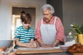 Grandmother with grandson preparing traditional easter meals, kneading dough for easter cross buns. Passing down family Royalty Free Stock Photo