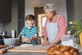 Grandmother with grandson preparing traditional easter meals, kneading dough for easter cross buns. Passing down family Royalty Free Stock Photo