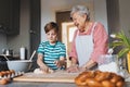 Grandmother with grandson preparing traditional easter meals, kneading dough for easter cross buns. Passing down family Royalty Free Stock Photo