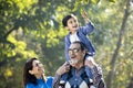 Grandmother with grandson sitting on grandfather`s shoulder at park