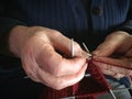 Grandmother hands knit red wool yarn. Senior lady, granny in blue knitted sweater handmade. needle pattern from thread loop. cl