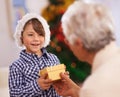 Grandmother, happy kid and giving Christmas gift in home, love and care at party. Xmas, grandma and child with present Royalty Free Stock Photo