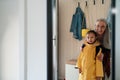 Grandmother helping granddaughter to get ready to leave home for school.