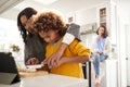 Grandmother helping her granddaughter prepare food in the kitchen, mother sitting in the background, focus on foreground