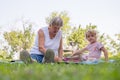 Grandmother with her grandaughter casually sitting on a blanket reading and talking in a park. Royalty Free Stock Photo